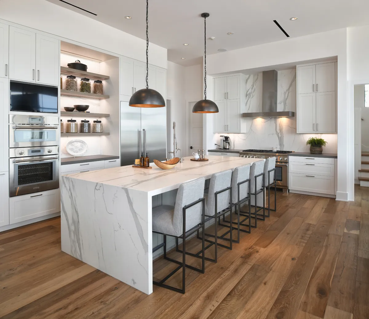 Marble waterfall island kitchen with bronze pendants